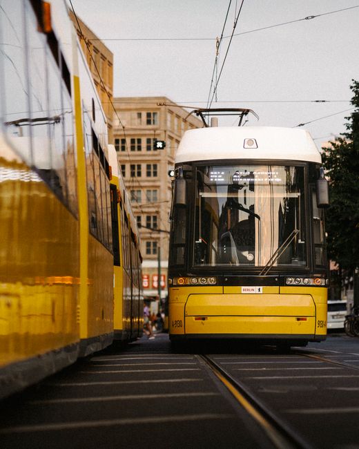 A yellow tram rides through the streets of Berlin, showcasing urban public transportation.