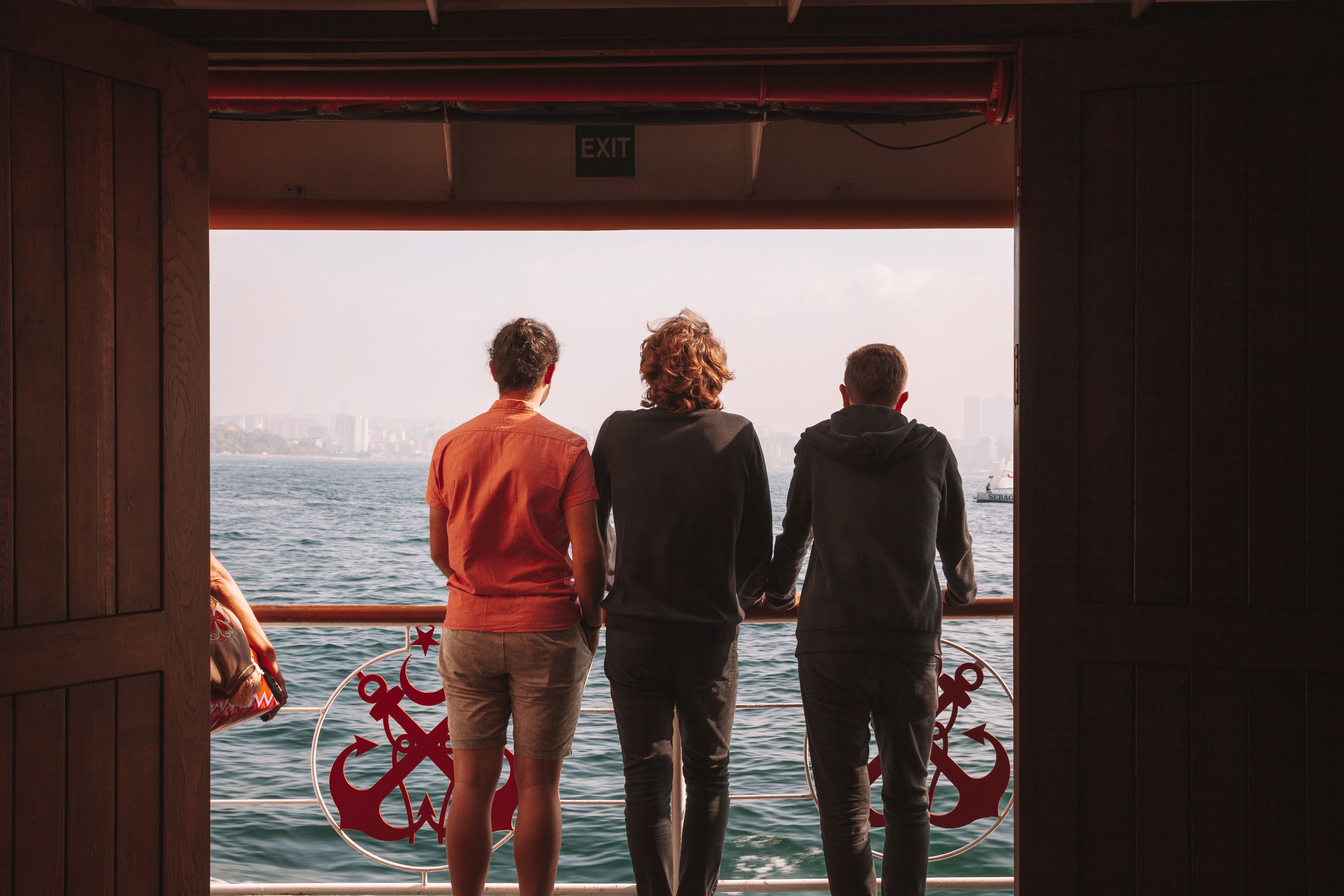 Three men sightseeing the Bosphorus from a ferry in Istanbul, Turkey.