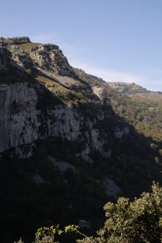 Breathtaking view of rocky hills and lush forests under clear blue skies in Cantabria, Spain.