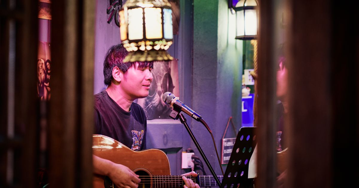 A musician playing the acoustic guitar and singing at a cozy indoor venue.