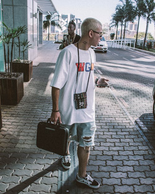 Homem De Camiseta Branca Segurando A Bolsa Enquanto Olha Para O Lado Esquerdo