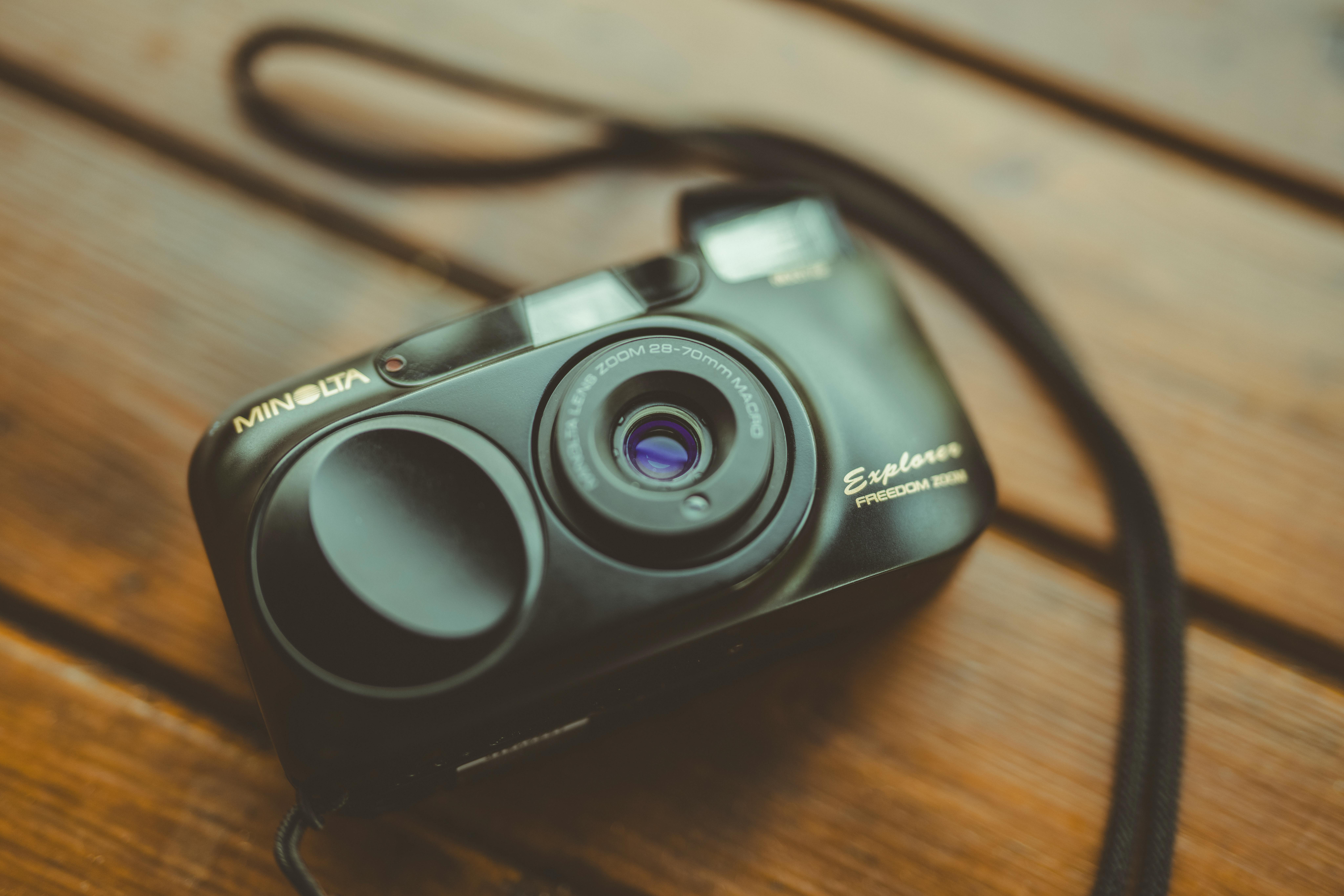 A classic Minolta film camera with strap resting on a rustic wooden surface, evoking nostalgia.