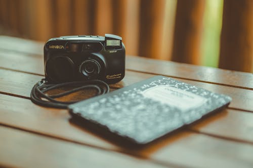 Notebook and Analogue Camera on a Table 