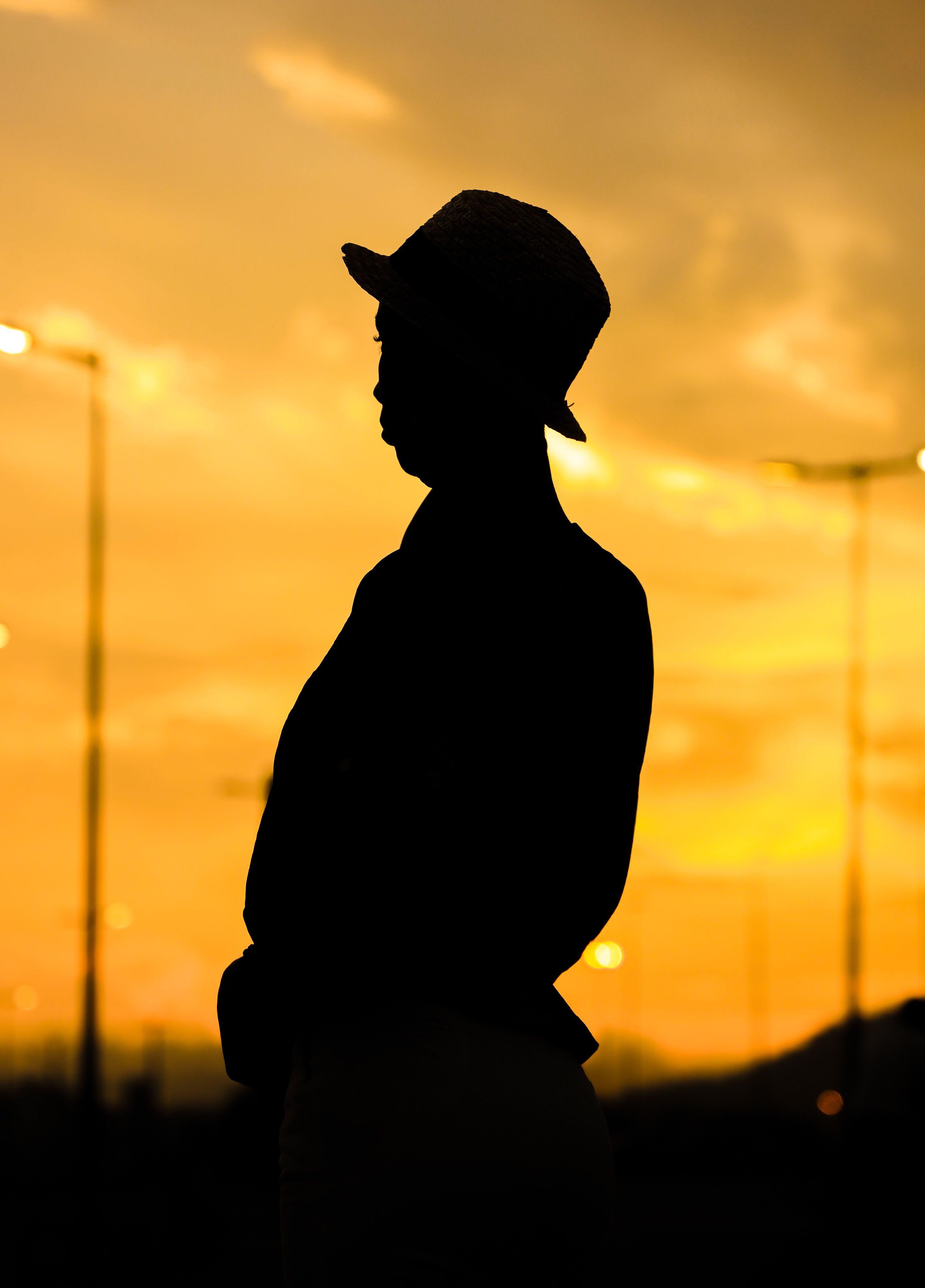 A person in silhouette wearing a hat against a vivid yellow sunset.. person, silhouette, wearing