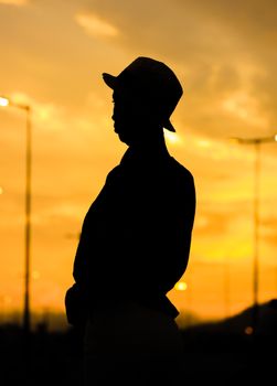 A person in silhouette wearing a hat against a vivid yellow sunset.. person, silhouette, wearing