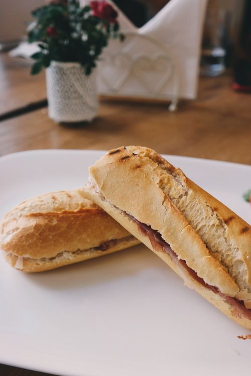 Free Delicious baguette sandwich with ham served on a white plate in a cozy setting. Stock Photo