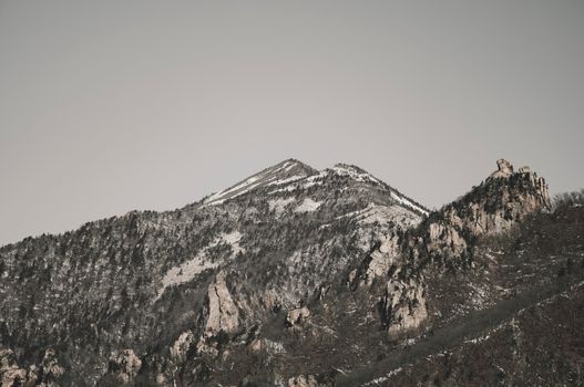 A serene snow-covered mountain peak reaching into a vast, clear sky.