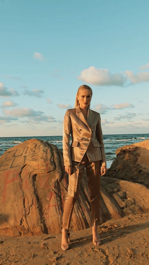 Woman in Suit Posing by Rocks on Sea Shore