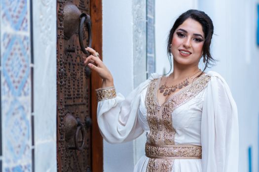 Portrait of a woman in traditional dress posing by an ornate door with intricate designs.