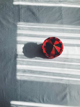Vibrant red and green toy casting shadows on a textured surface with sunlight.