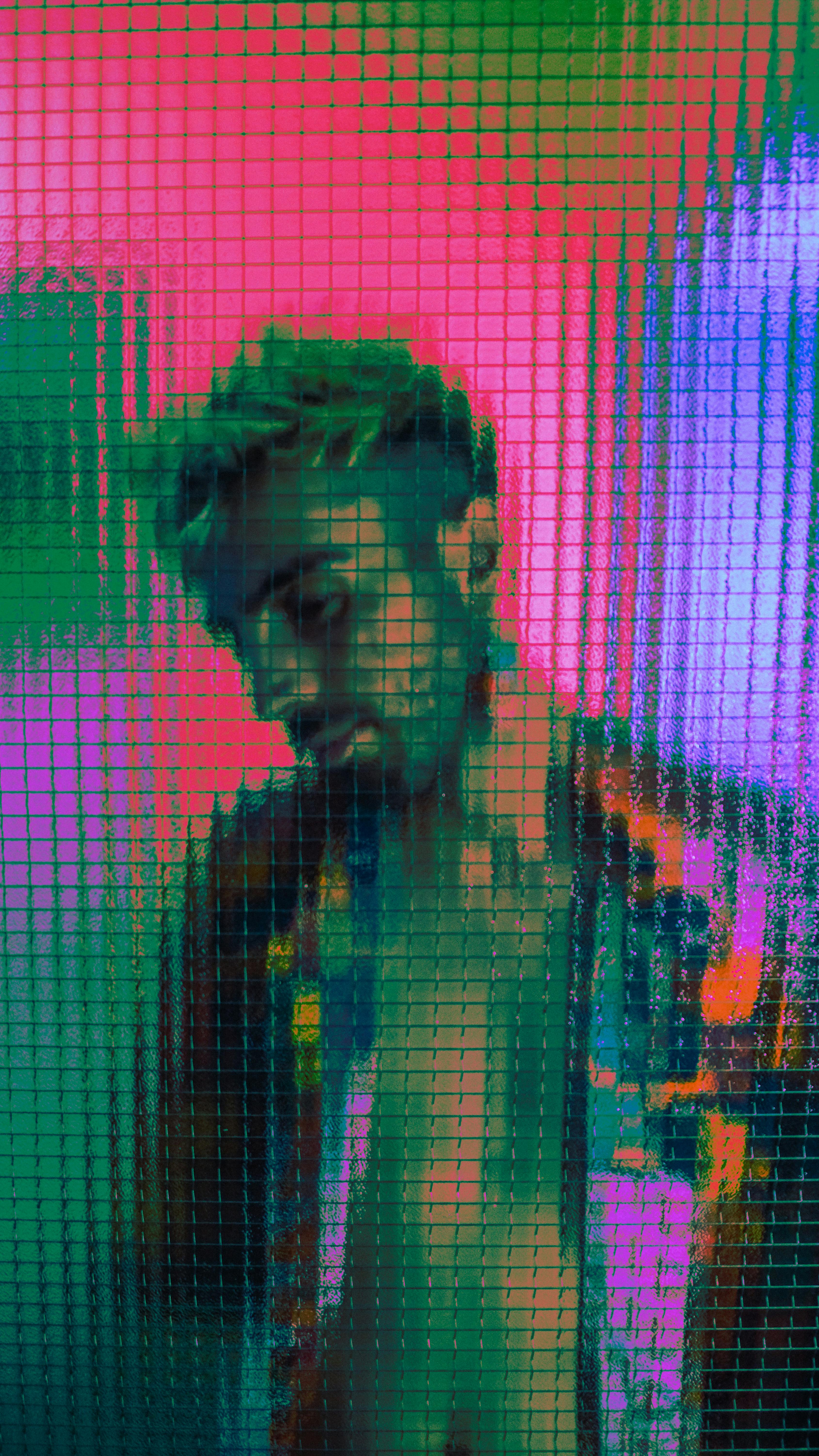 Vibrant portrait of a man viewed through a textured glass surface with colorful lighting.