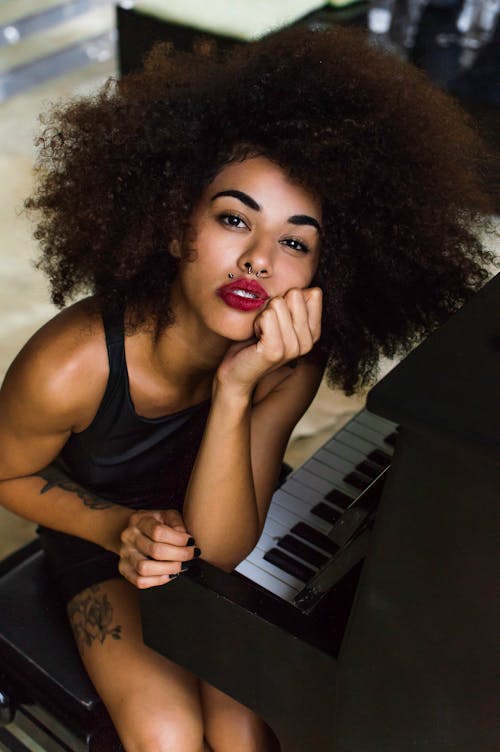 免费 戴着红色唇膏坐在钢琴旁的女人 素材图片