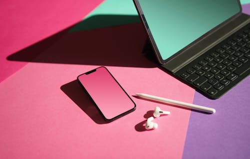 Stylus Pen Earpods and Smartphone by Laptop on Desk