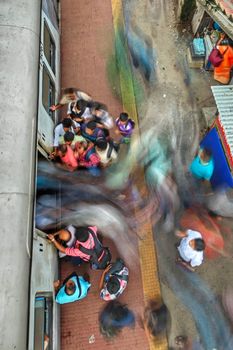 Dynamic scene of commuters boarding a train at Barasat Station, India.