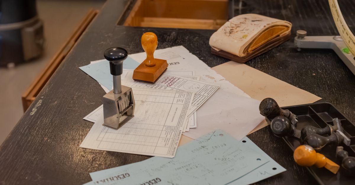 Cluttered desk with office stamps on top of various documents in an office setting.