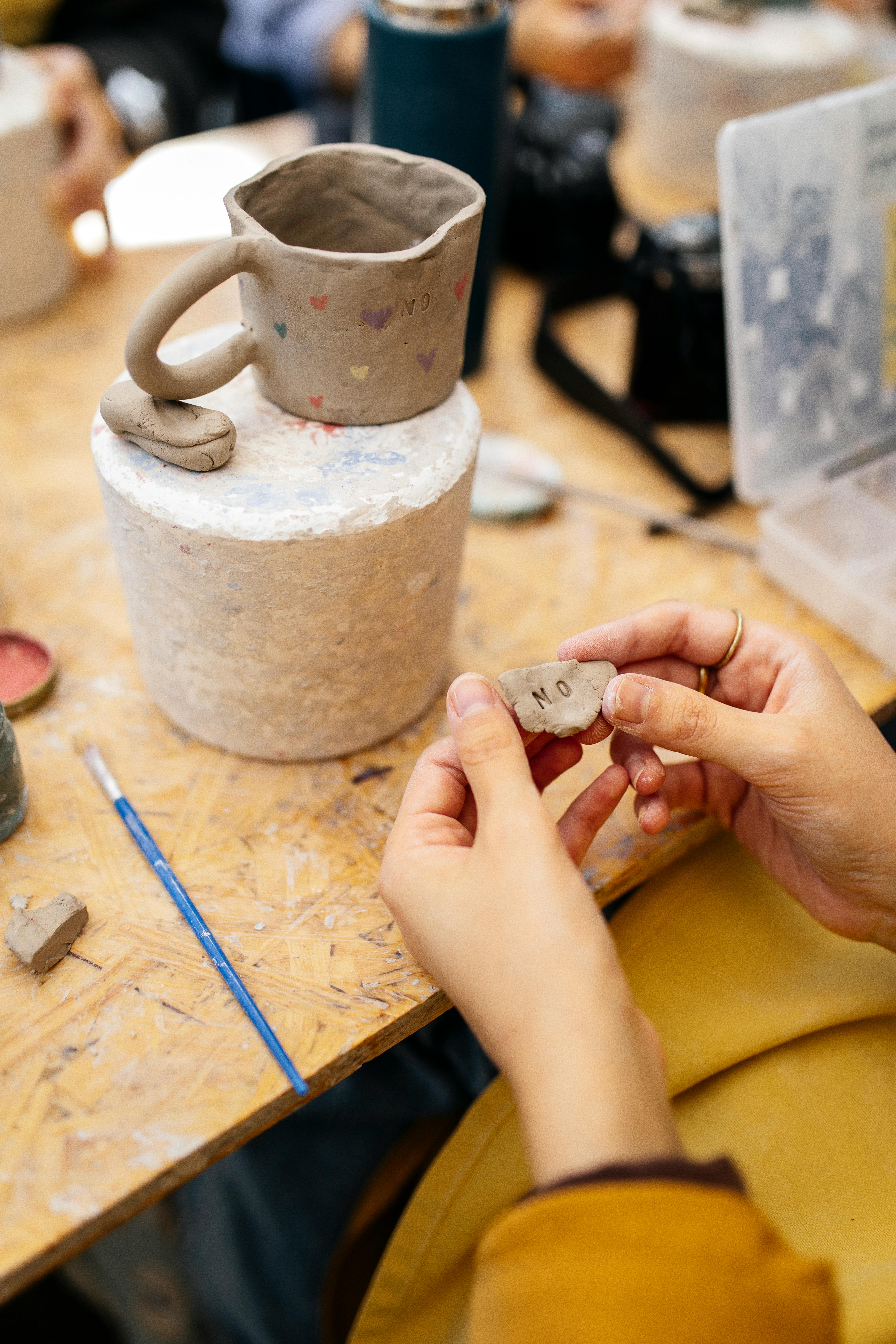 Person holding clay for handmade mug in artistic workshop environment.