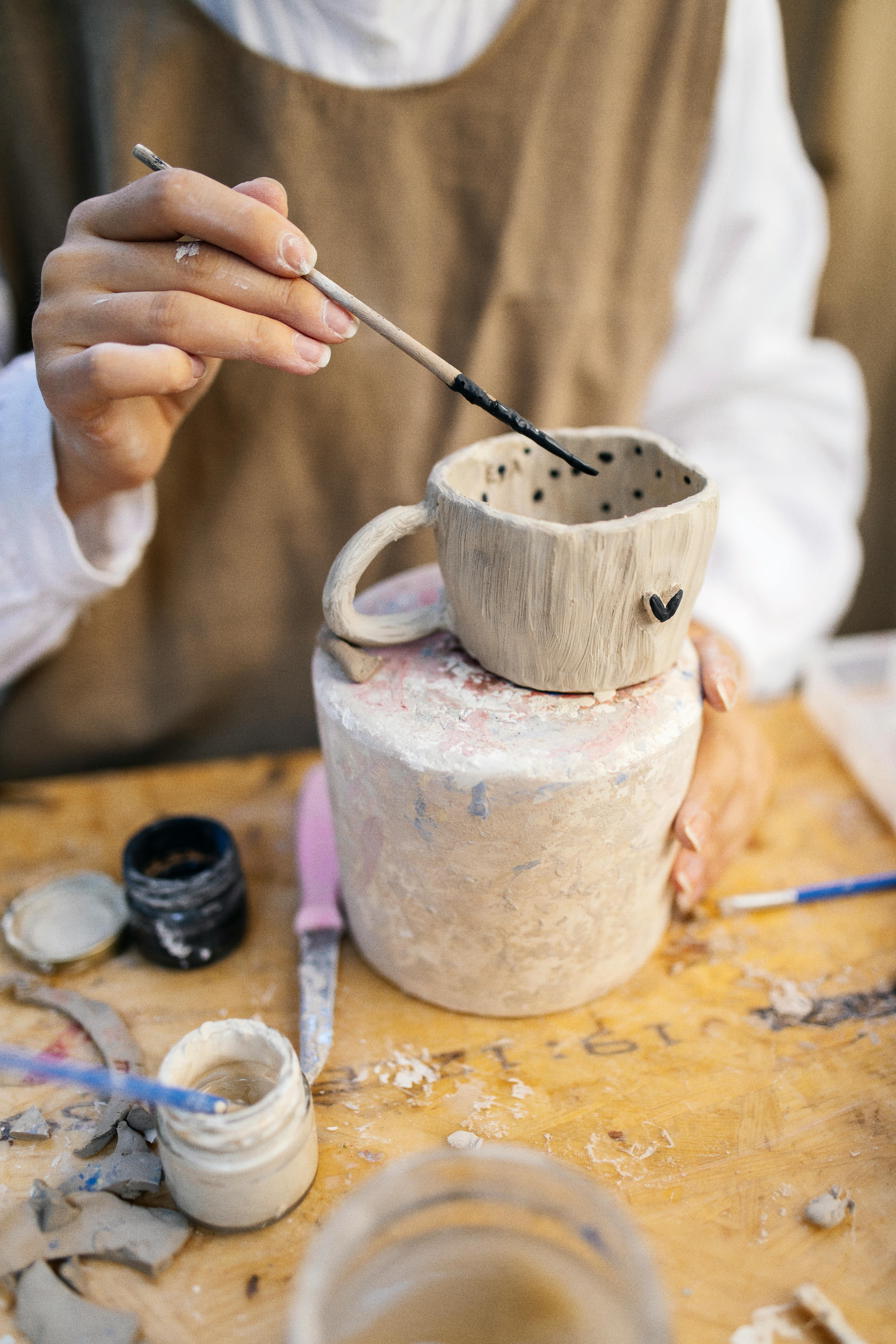 Artist painting a ceramic mug with dot patterns in an artistic workshop.