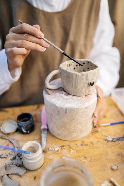 Free Artist painting a ceramic mug with dot patterns in an artistic workshop. Stock Photo