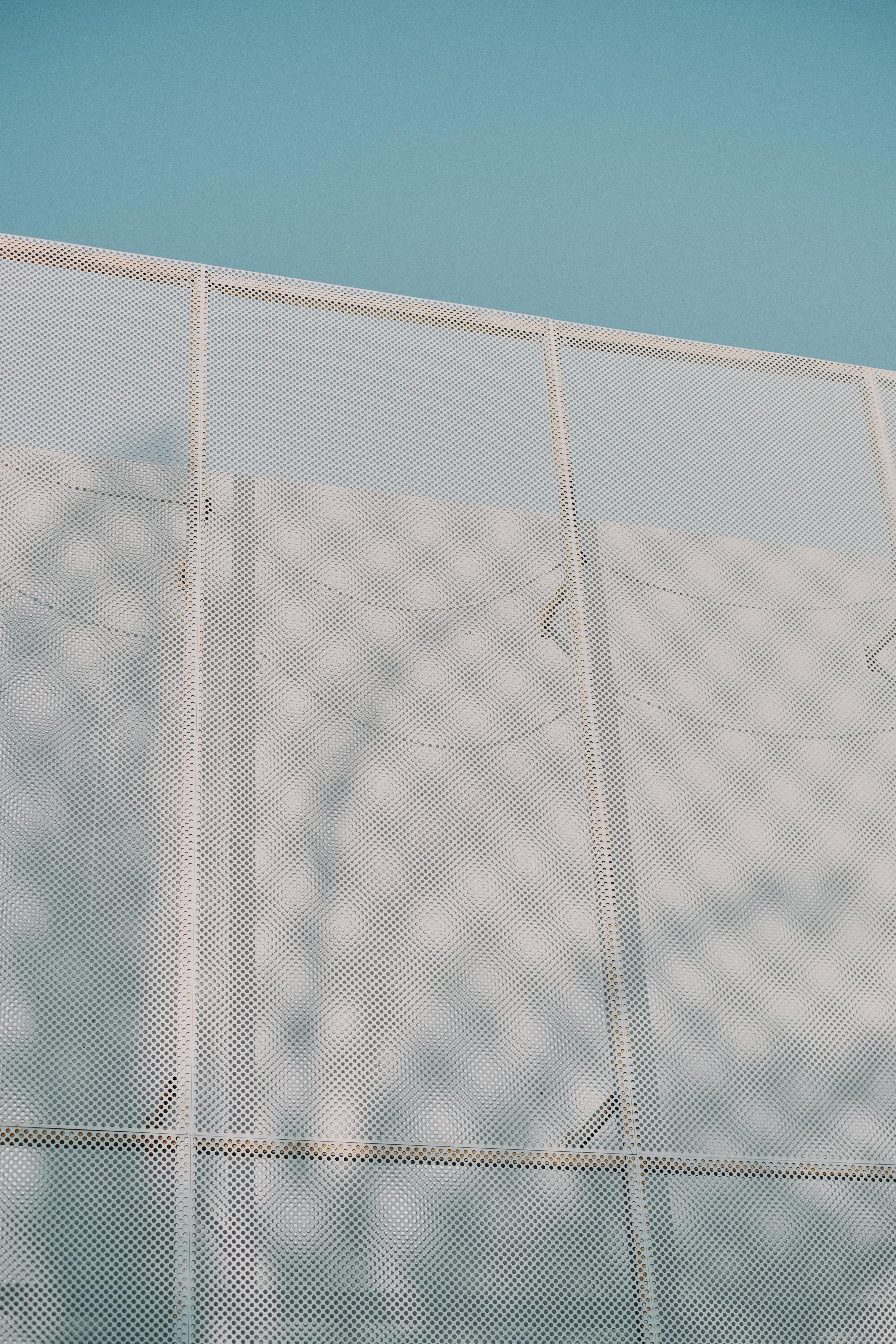 Free Low angle view of a white mesh wall against a clear blue sky in Dubai, UAE. Stock Photo