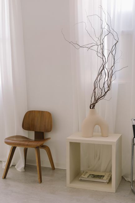 Stylish minimalist interior with wooden chair, white curtains, and elegant decor.