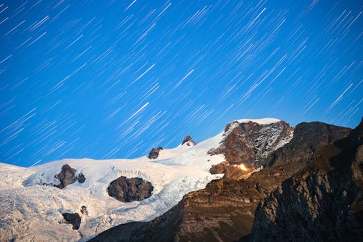 Captivating star trails illuminate the night sky over snowy alpine peaks, offering a magical view.