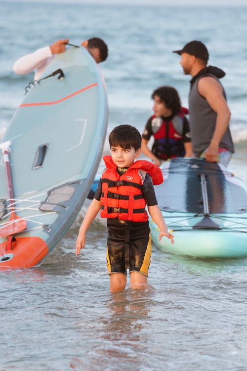Free Child and family paddleboarding at the beach, fun summer activity in shallow water. Stock Photo