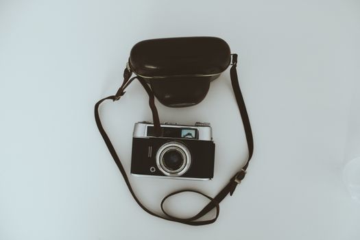Retro camera with case on a clean surface, showcasing vintage photographic equipment with a minimalist style.