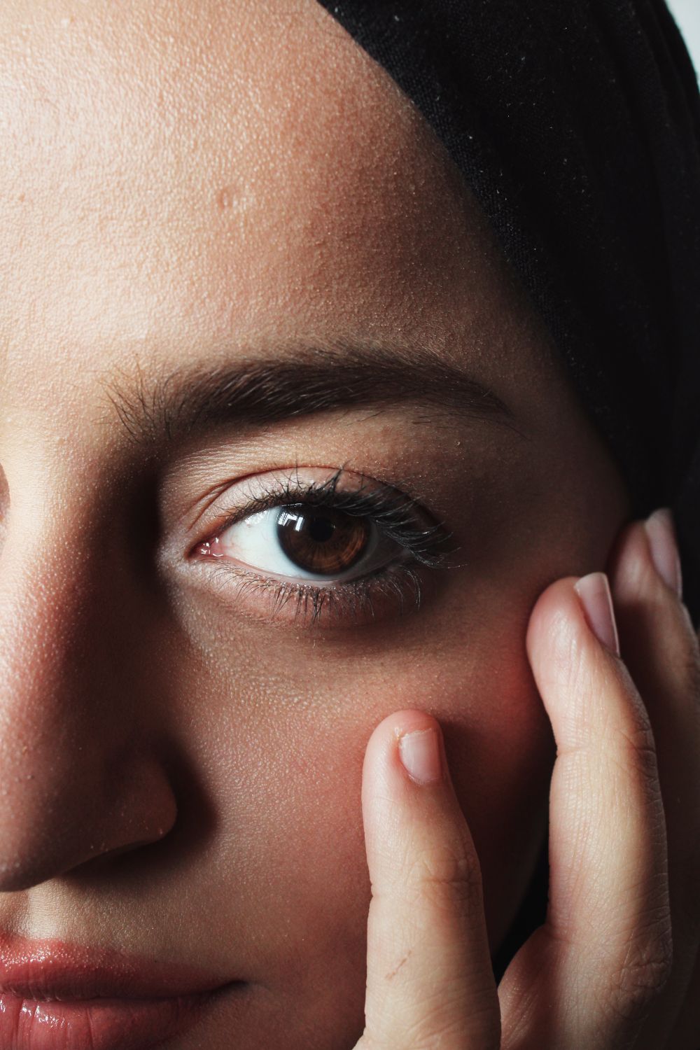 A close portrait of a woman gently touching her cheek