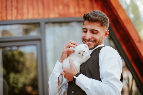 Elegant Man Holding a Kitten and Smiling 