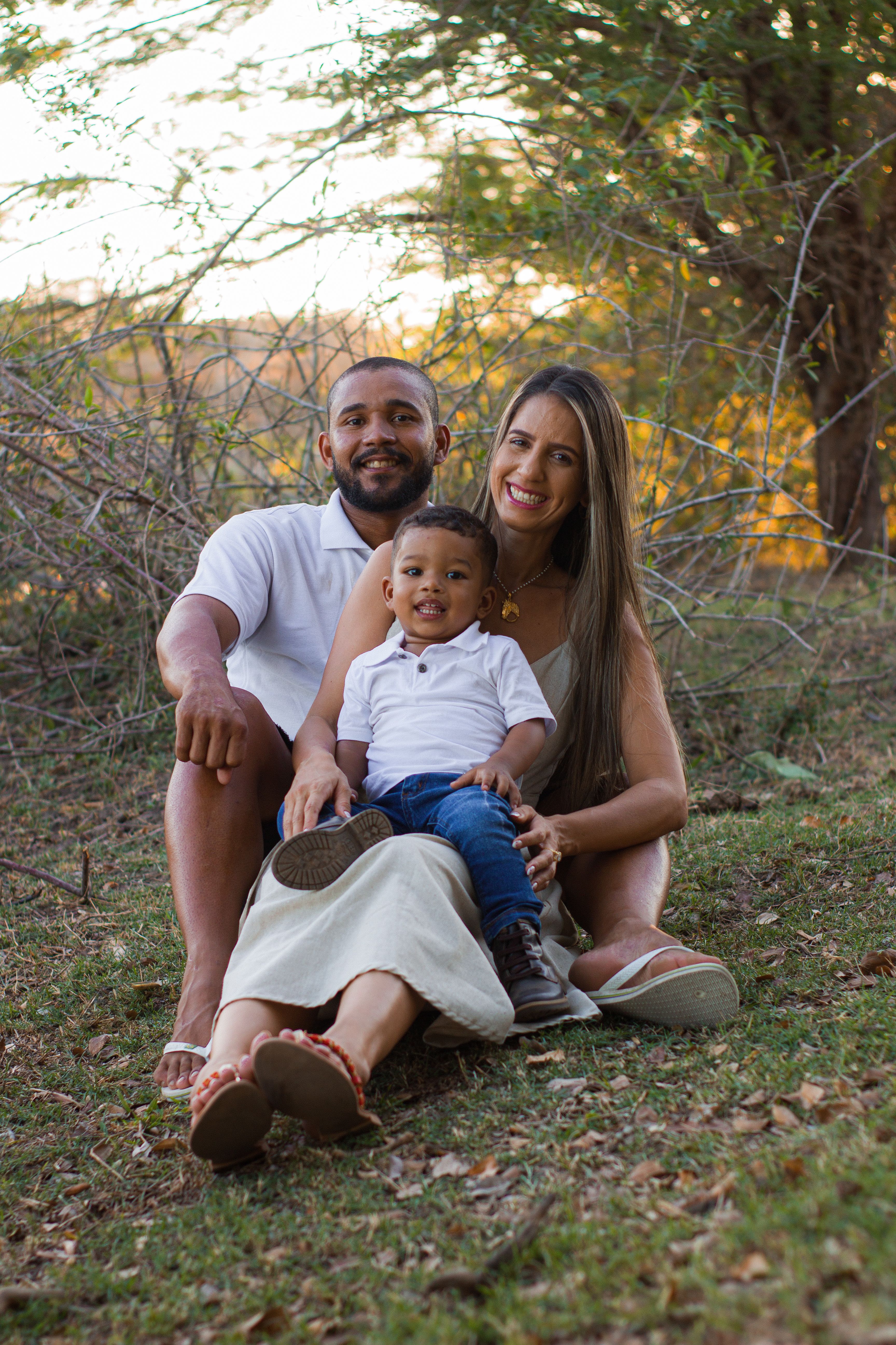 A joyful family of three enjoying a sunny day outdoors in a natural setting.