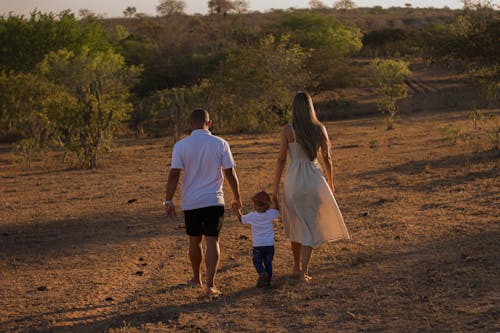 Parents Leading their Little Son by Hands