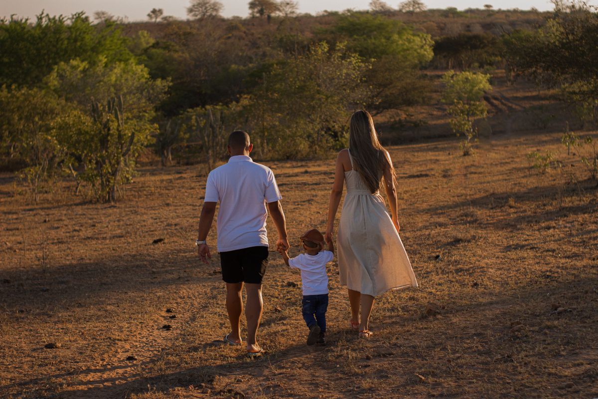 Parents walking hand in hand with their young son at sunset in a rural setting