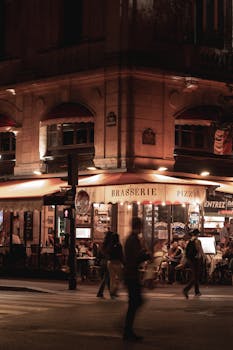 Nighttime street scene featuring a lively Parisian brasserie with people and warm lighting.