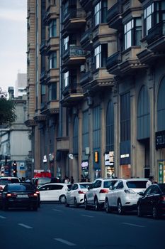 Traffic and pedestrians along a bustling street in downtown Baku under evening skies.