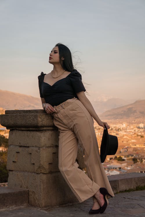 Model Wearing a Black Blouse and Beige Pants with a Crease 