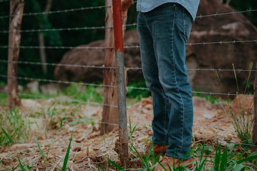 Man in Jeans with Shovel in Hand Standing by Fence