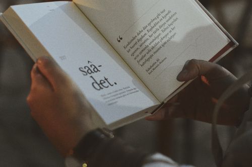 Free Person holding and reading an open book with visible text. Stock Photo