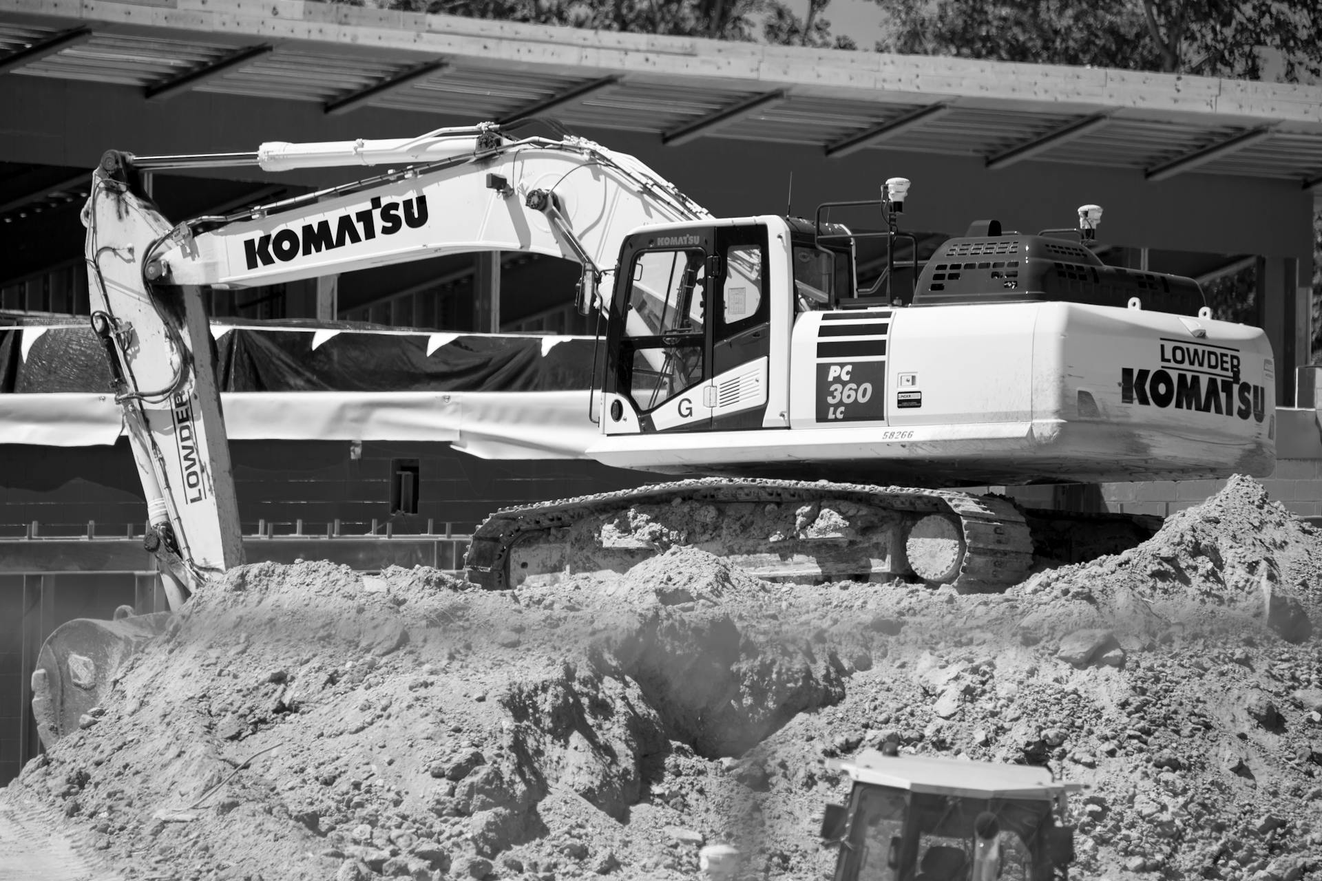 Monochrome image of a Komatsu excavator on a construction site.