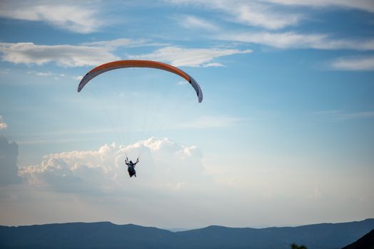 Enjoy the thrill of paragliding over Belo Horizonte with breathtaking mountain views in a clear blue sky.