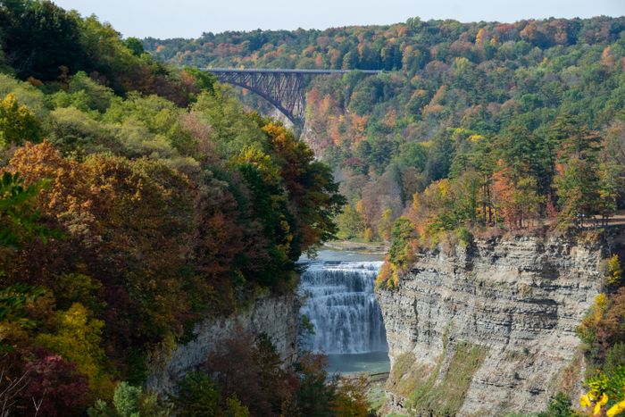 A waterfall and bridge surrounded by autumn foliage at Letchworth State Park in Upstate New York