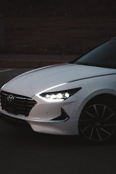 Low-light image of a white Hyundai car on dark city streets in Islamabad, Pakistan.
