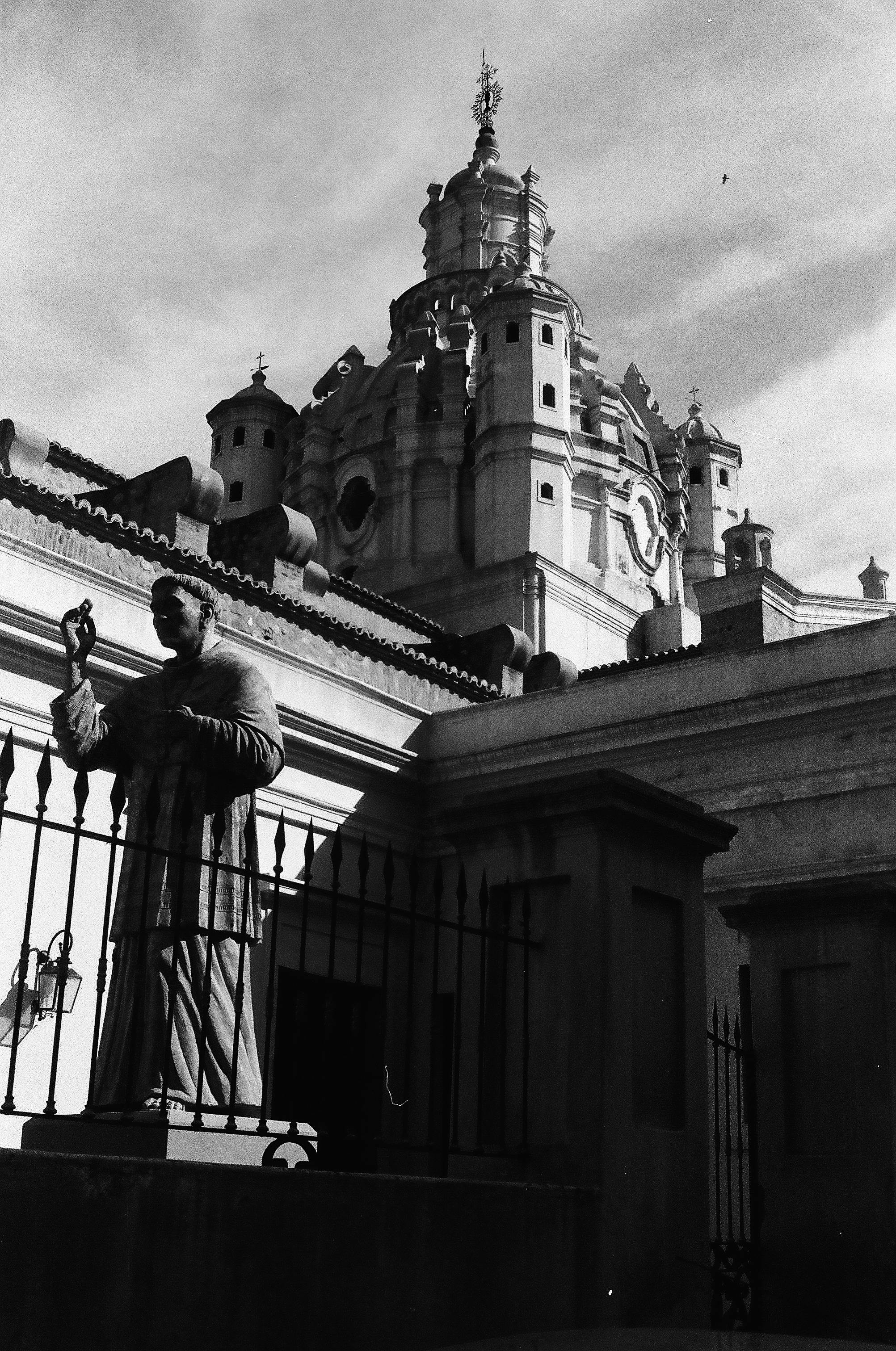 Black and white image of a historic church with a sculpture in Córdoba, Argentina, offering a classic architectural view.