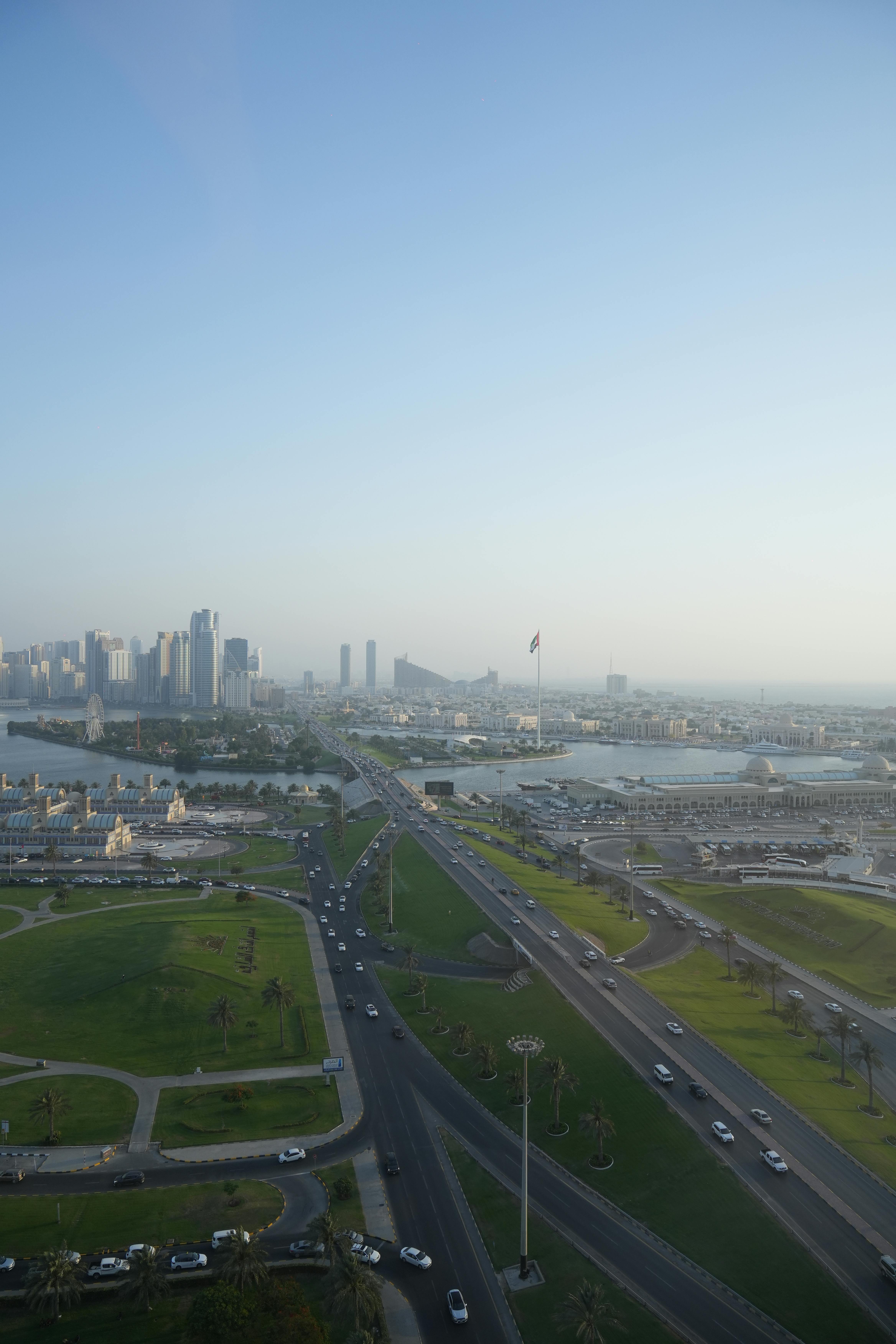 Stunning aerial view capturing Sharjah's modern skyline and green spaces under a clear sky.