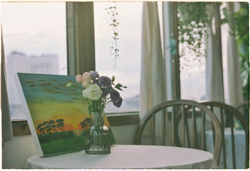 Free A calming scene of a table with painting and flowers by a window, creating a tranquil atmosphere indoors. Stock Photo
