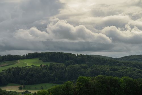 Free Aerial view of a lush green forest and hills under a dynamic, cloudy sky. Stock Photo
