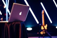 桌子上放着一台时尚的笔记本电脑，背景是明亮的霓虹灯和一把吉他