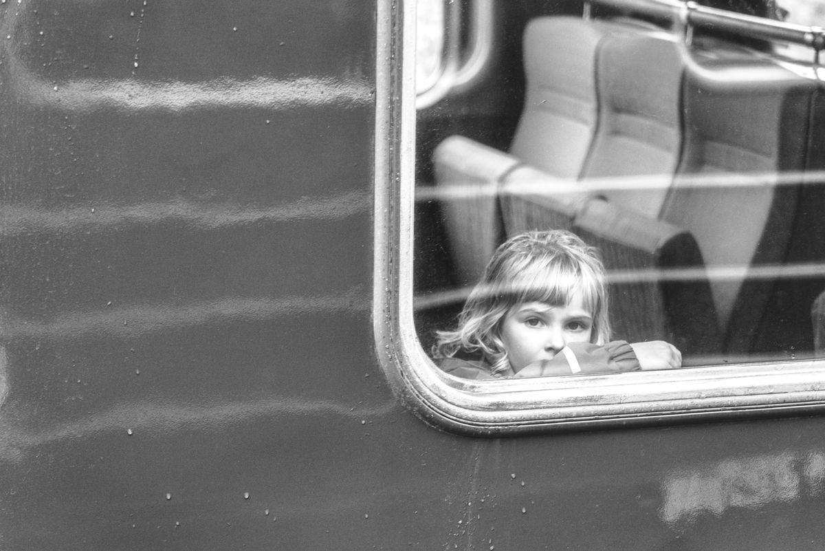 A traveler framed behind a rain-streaked train window