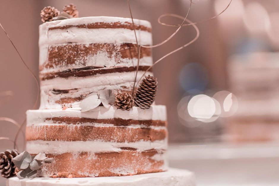 A rustic iced cake decorated with pinecones, creating a cozy, warm aesthetic.