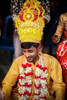 A joyous cultural celebration featuring a man in intricate traditional attire with a floral garland.