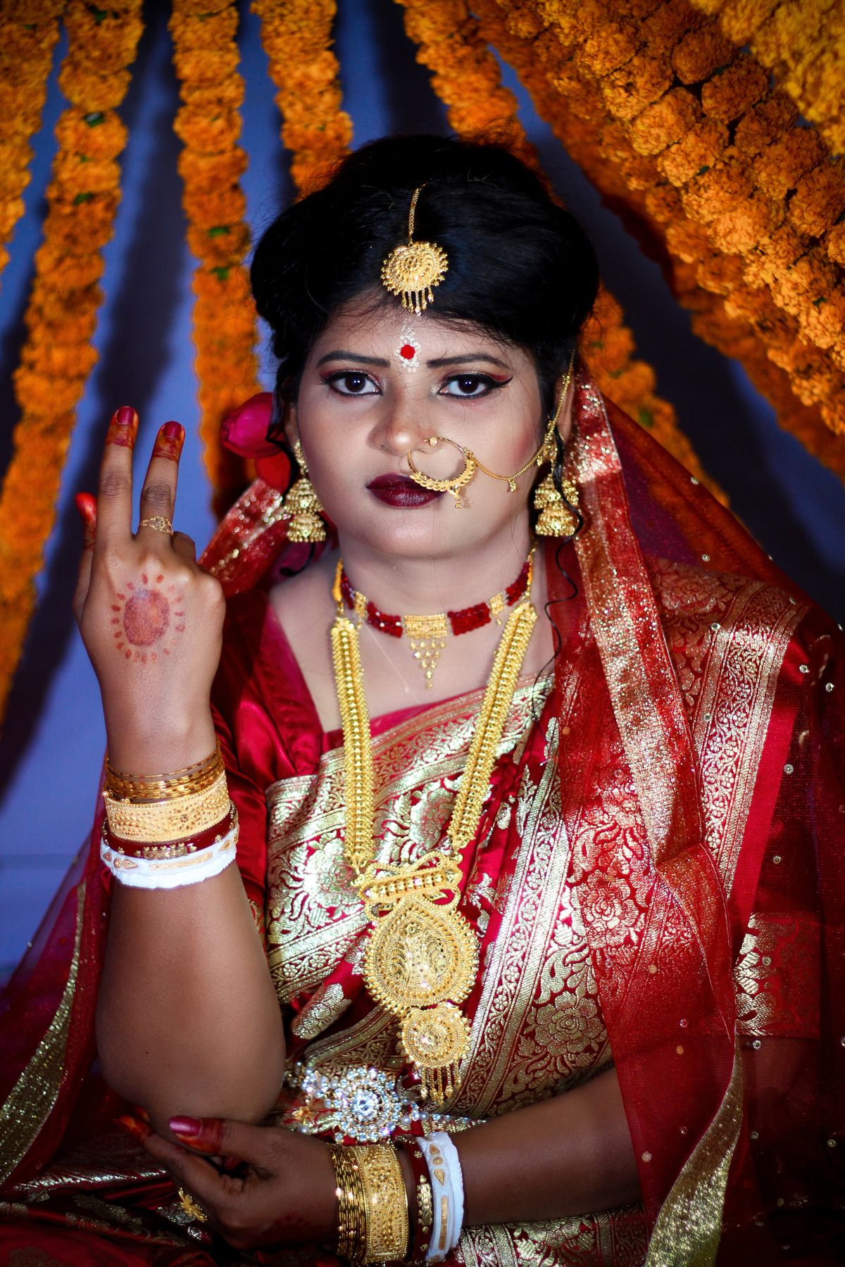 Bride in a red and gold bridal lehenga with marigolds